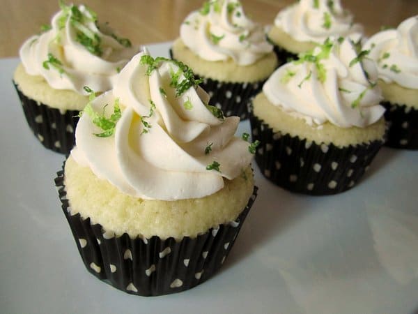 a closeup of margarita cupcakes in black and white polka dot liners on a white platter