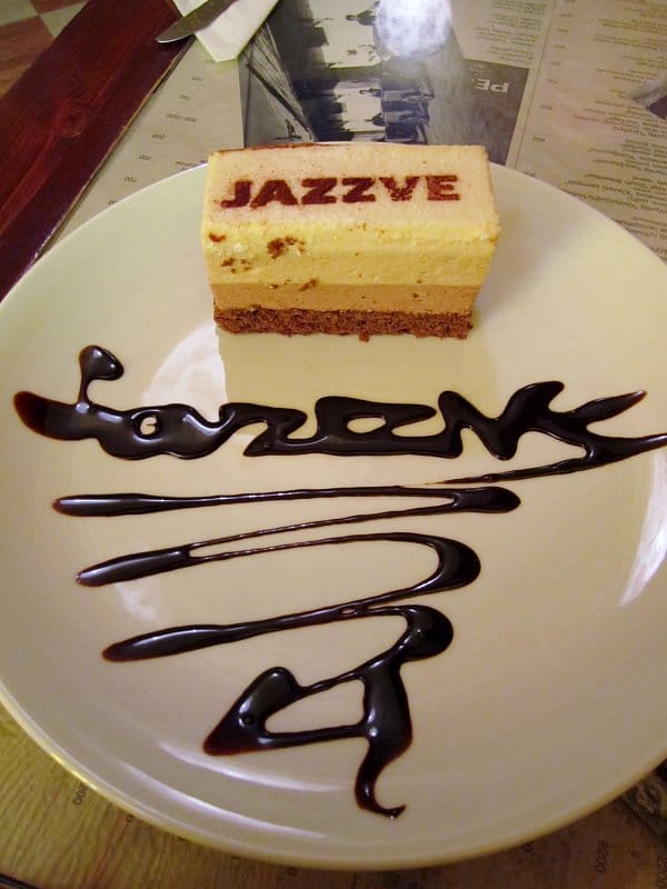 A piece of cake on a plate with Jazzve written on the plate in chocolate syrup