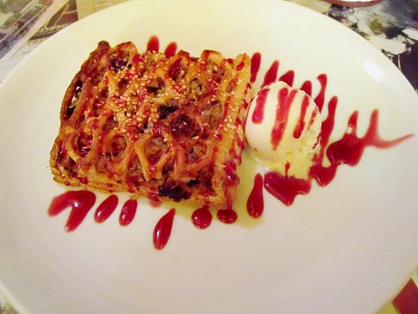 overhead view of a fruit tart with ice cream and drizzled with red berry sauce