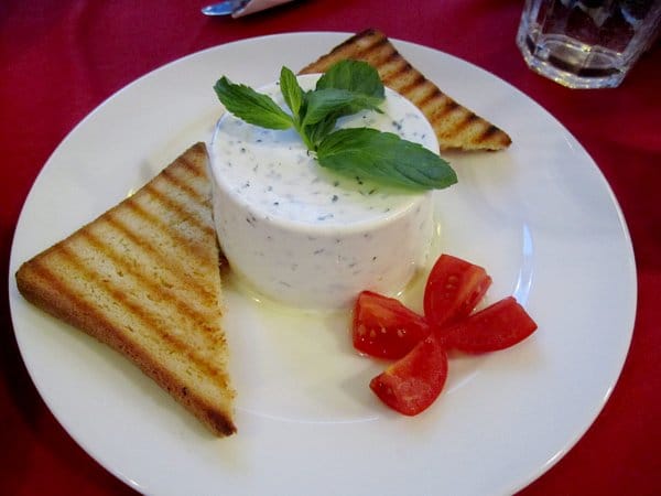 pieces of toast on either side of a white cylinder topped with basil