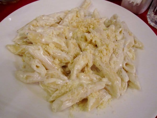 a plate of penne pasta in creamy sauce topped with cheese