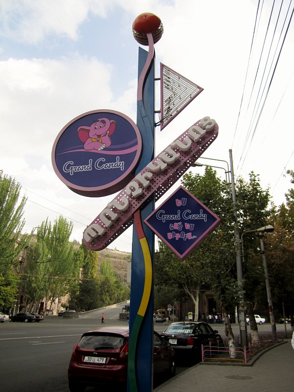 An outdoor sign that says Grand Candy with the image of a pink elephant