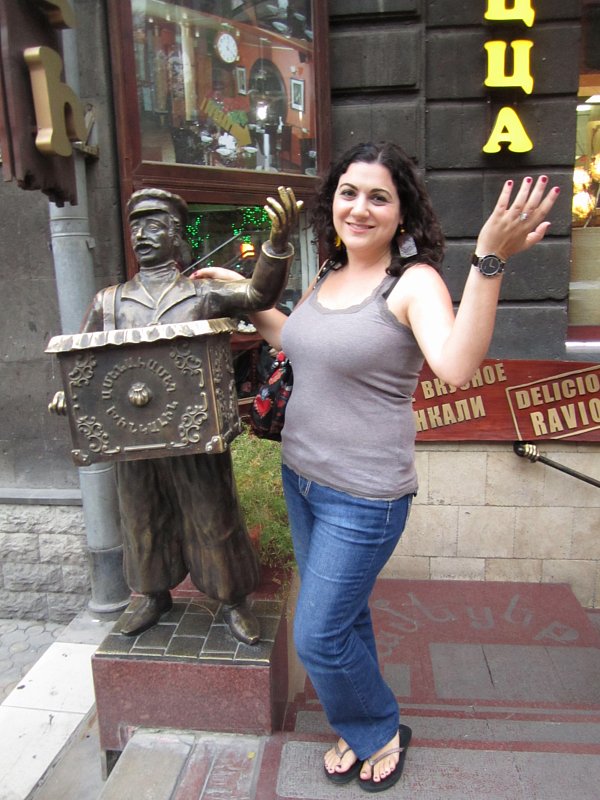 A woman standing next to a statue and posing like the statue