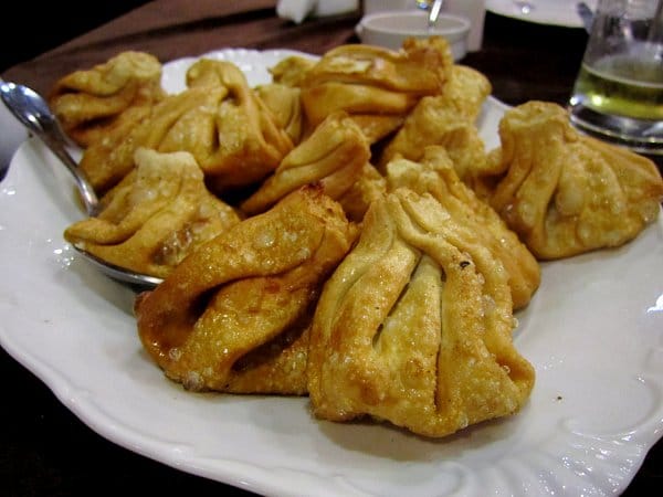 a white platter of deep-fried khinkali dumplings