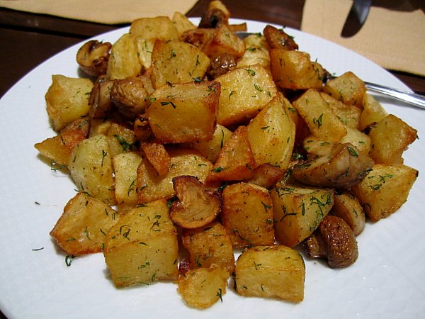 a white platter topped with cubed fried potatoes and mushrooms