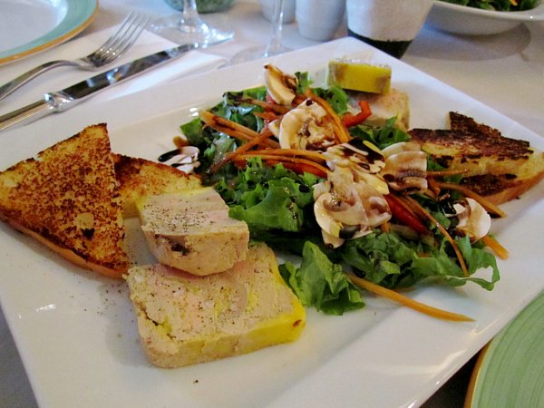 A plate of pate, bread, and salad on a table