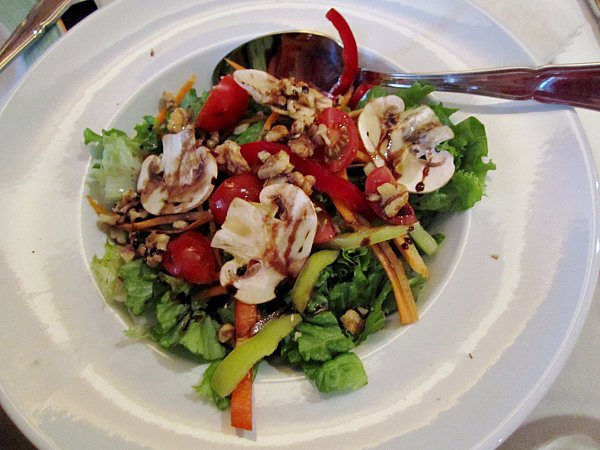 a bowl of salad with mushrooms, peppers, and cherry tomatoes