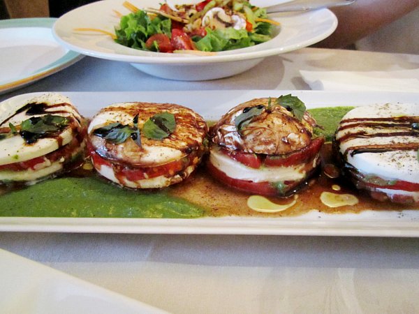 tomato and mozzarella stacks with pesto and balsamic vinegar on a white plate