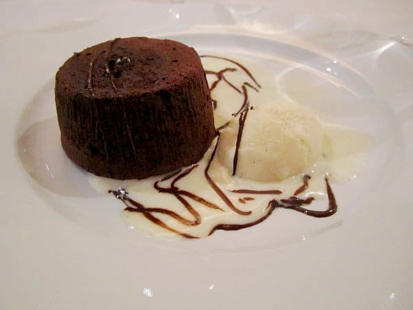 A round chocolate cake with ice cream on a plate