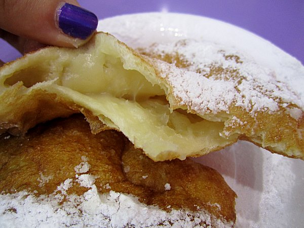 A half eaten doughnut filled with pastry cream