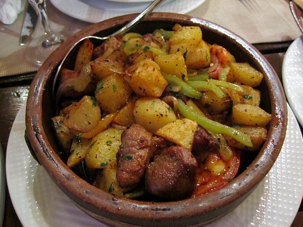 a bowl of fried potatoes with cubes of meat and green peppers