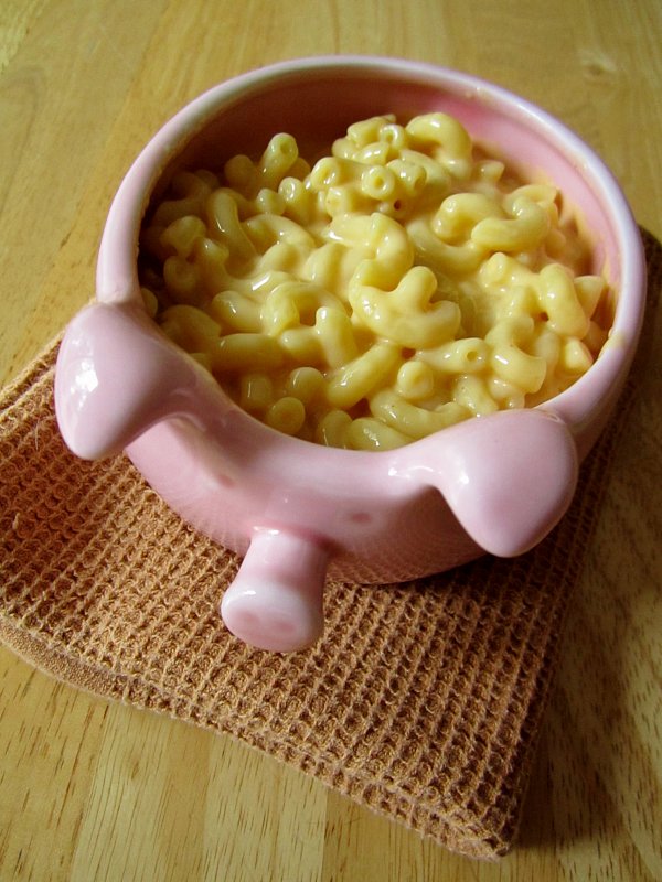 a pink bowl shaped like a pig filled with macaroni and cheese