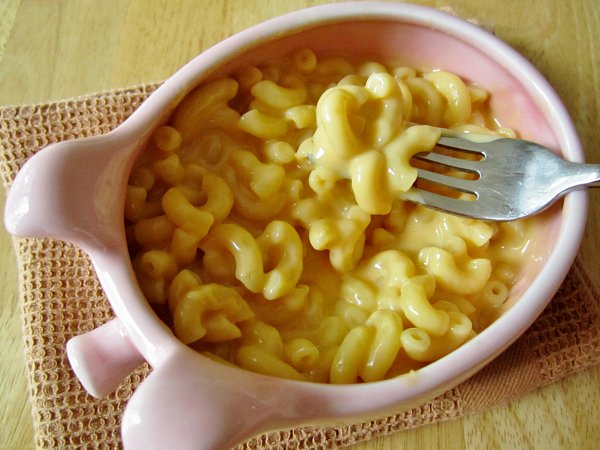 overhead view of a pink pig-shaped bowl filled with macaroni and cheese
