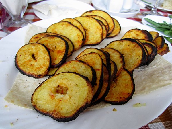 sliced cooked potatoes arranged in rows on a white platter