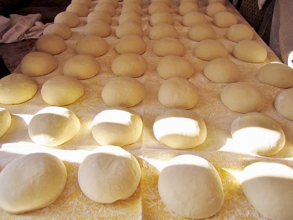 rows of bread dough balls lining a large table