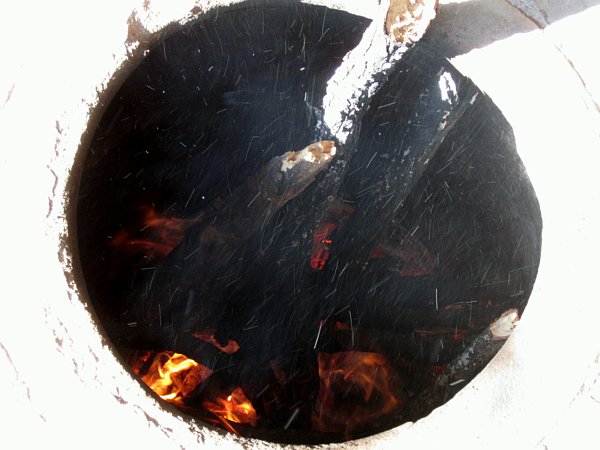 view looking down at a fire in a tonir underground oven