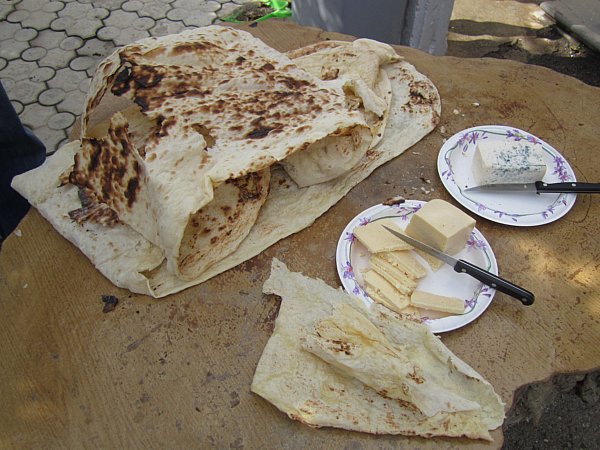 piles of lavash flatbread and plates of cheese on a wooden table