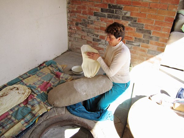 a woman sitting on the ground stretching a piece of dough between her hands