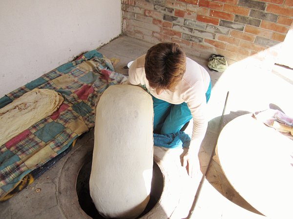 a woman sitting on the ground holding a large pillow lined with dough