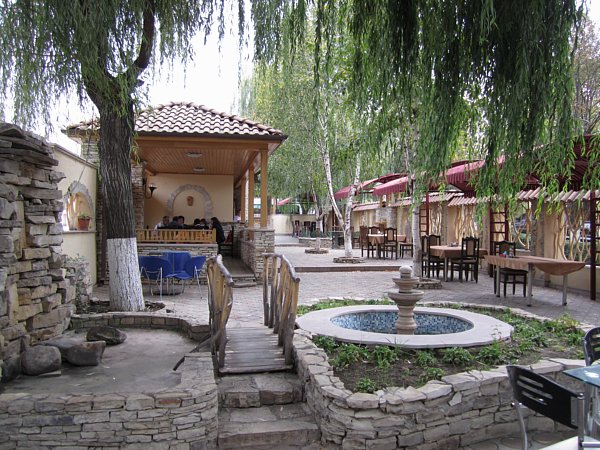 an outdoor garden space with a small fountain, tables and chairs