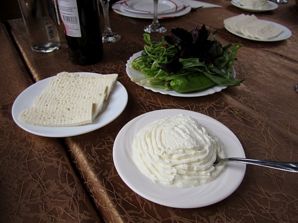 plates of cheese, strained yogurt, and herbs on a brown table