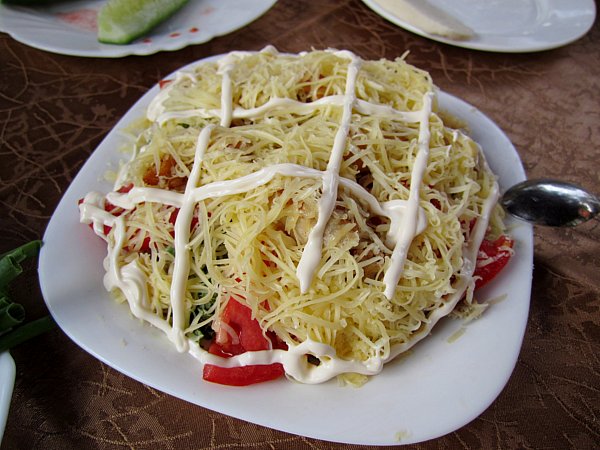 A plate of food topped with shredded cheese and white sauce