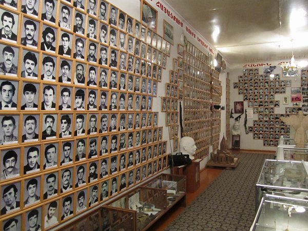 a room lined with framed photos of people on the walls