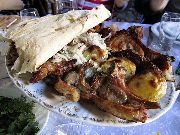 A closeup of grilled meats, potatoes, and bread on a platter