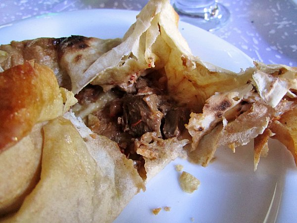 a closeup of a piece of crispy bread filled with braised beef