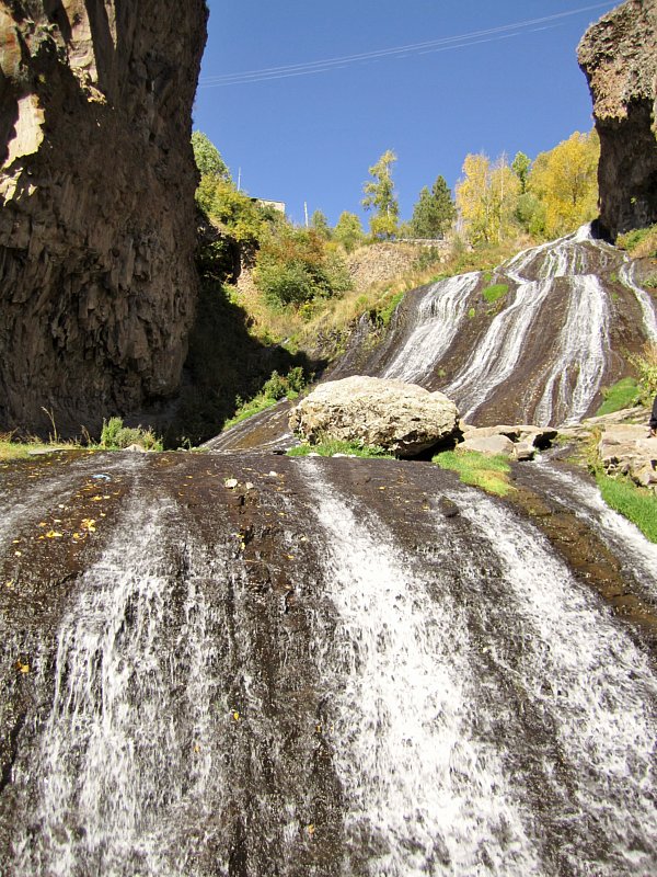 A waterfall with trees on the side of a mountain