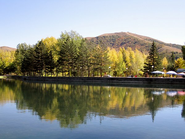 a still lake with trees and mountains in the background