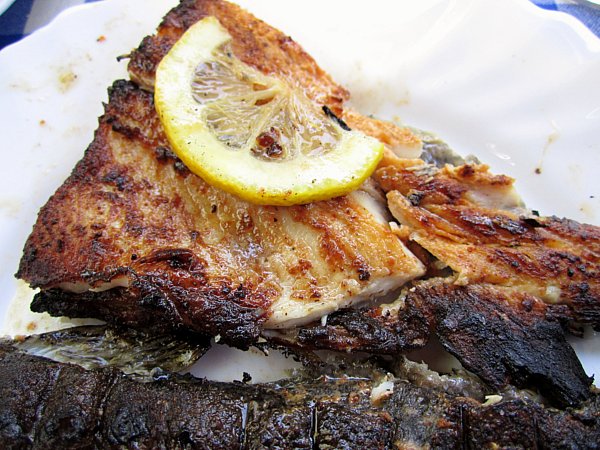 a closeup of a piece of cooked fish topped with a slice of lemon