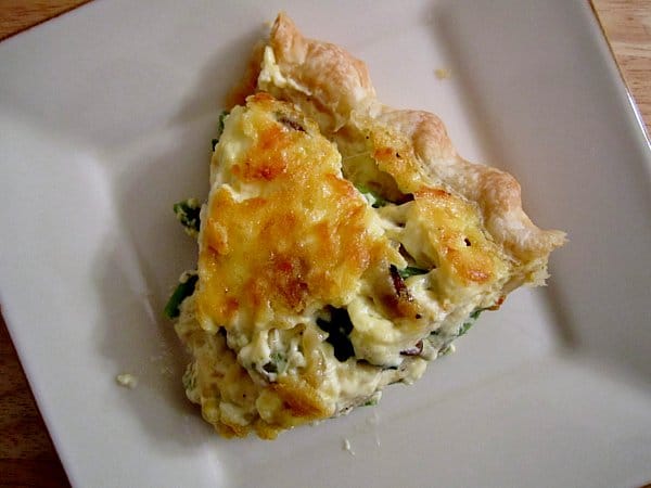 overhead view of a slice of quiche on a square white plate