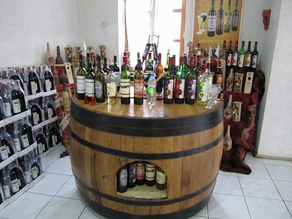 wide view of a wooden table resembling a wine barrel topped with bottles of wine