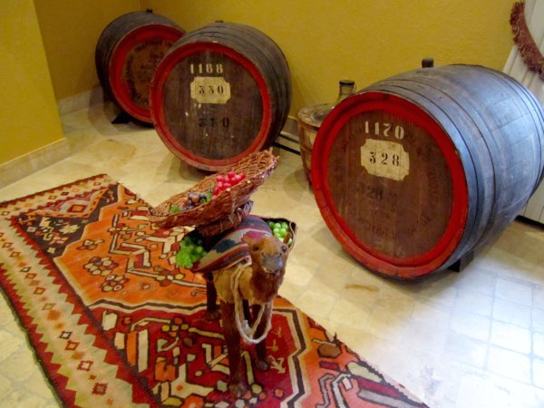 alcohol barrels with a figure of a camel standing in front on a colorful rug