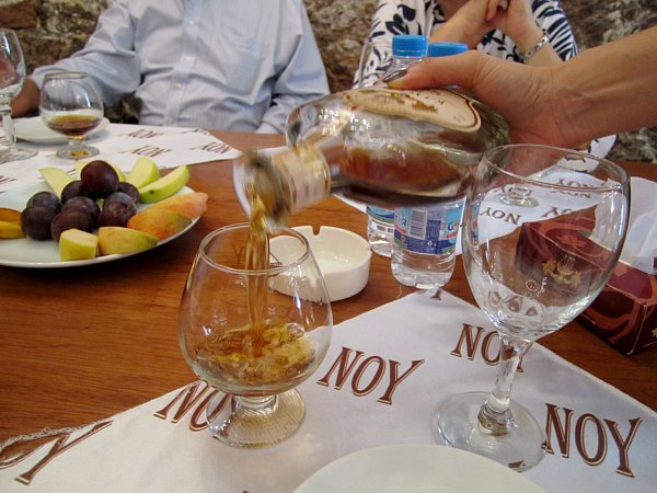 someone\'s hand pouring brandy into a glass on a table