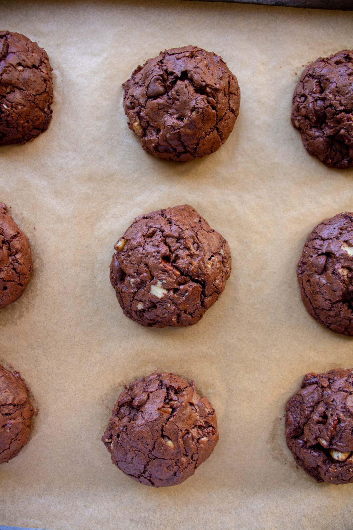 Baked brownie cookies on a parchment paper lined baking sheet.