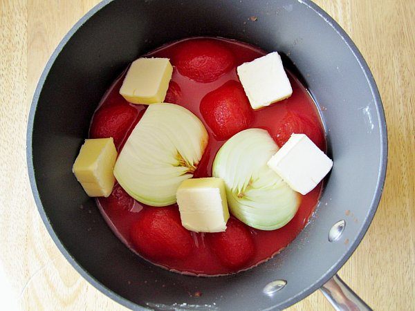 overhead view of a saucepan filled with tomatoes, onions and butter