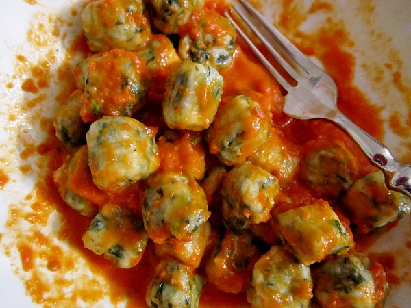 overhead view of a half eaten plate of gnudi dumplings in tomato sauce