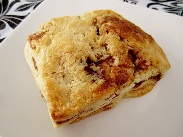 a closeup of a square cinnamon honey scone on a square white plate