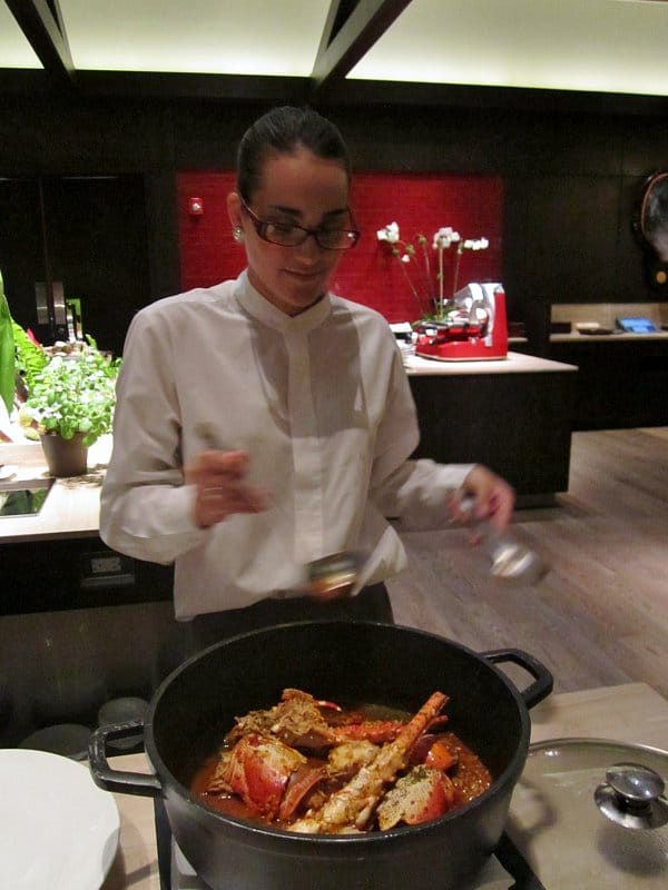 A woman standing behind a large pot of food