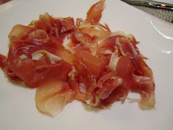 A closeup of sliced Spanish ham on a white plate