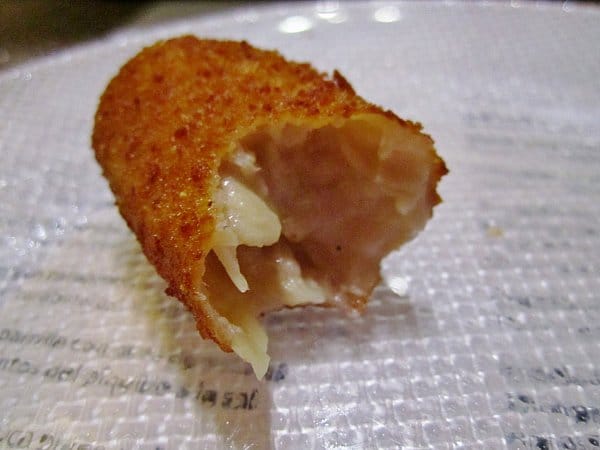 A half eaten fried croquette on a plate