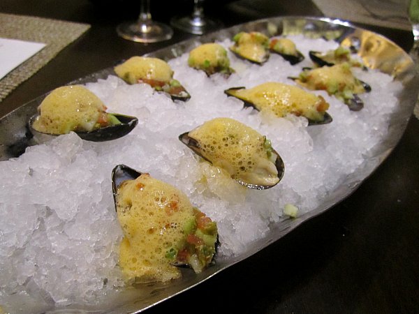 mussels on the half shell topped with foam on a bed of crushed ice