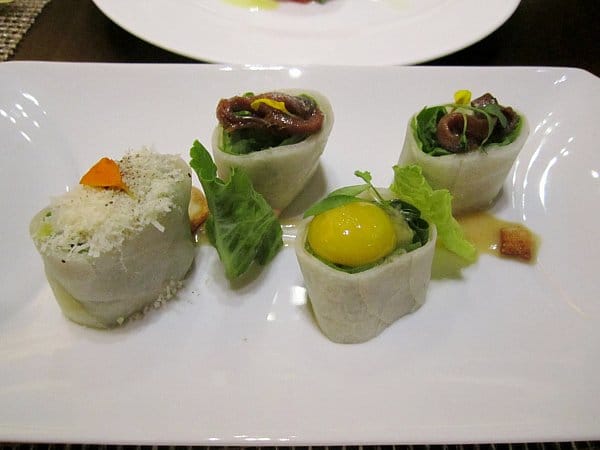 rolls topped with anchovies and egg yolk on a white plate