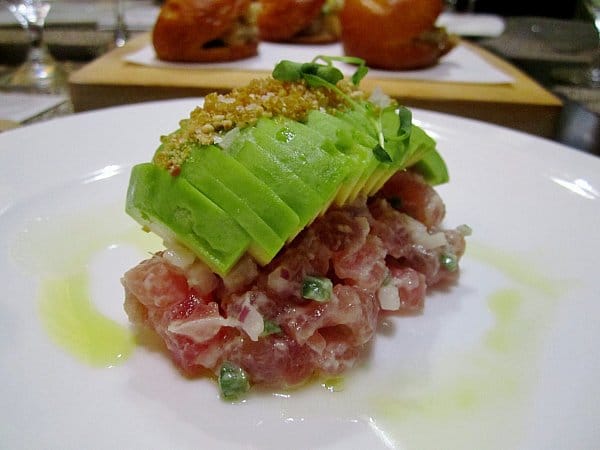 chopped raw tuna topped with sliced avocado on a white plate