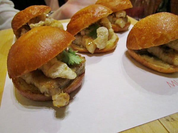 small buns filled with pork belly and chicharróns on a white surface