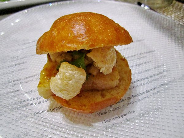 a small bun filled with pork belly and chicharróns