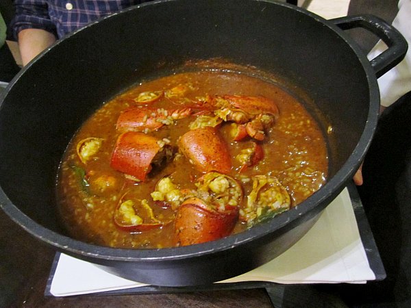 A big metal pot filled with soupy rice with lobster