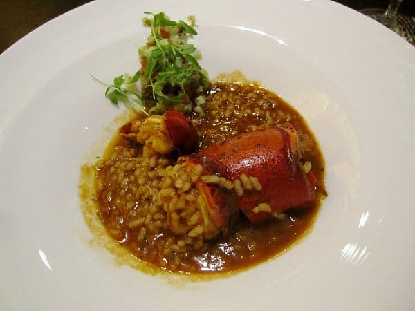 soupy rice with lobster served in a wide white bowl